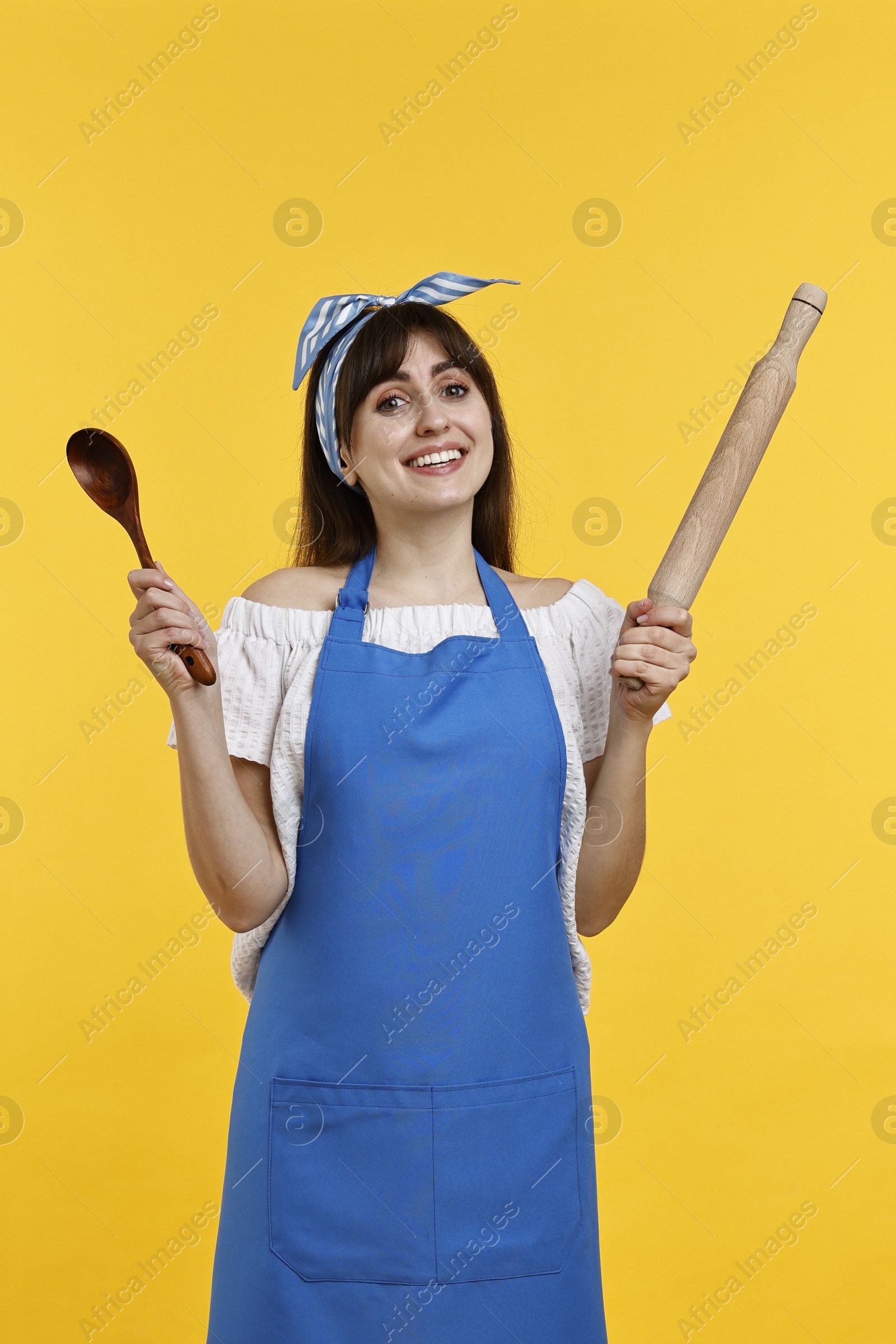 Photo of Woman with rolling pin and spoon on yellow background