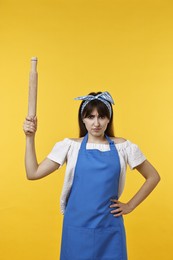 Photo of Angry woman with rolling pin on yellow background