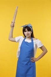 Photo of Angry woman with rolling pin on yellow background