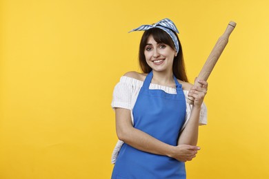 Photo of Happy woman with rolling pin on yellow background. Space for text