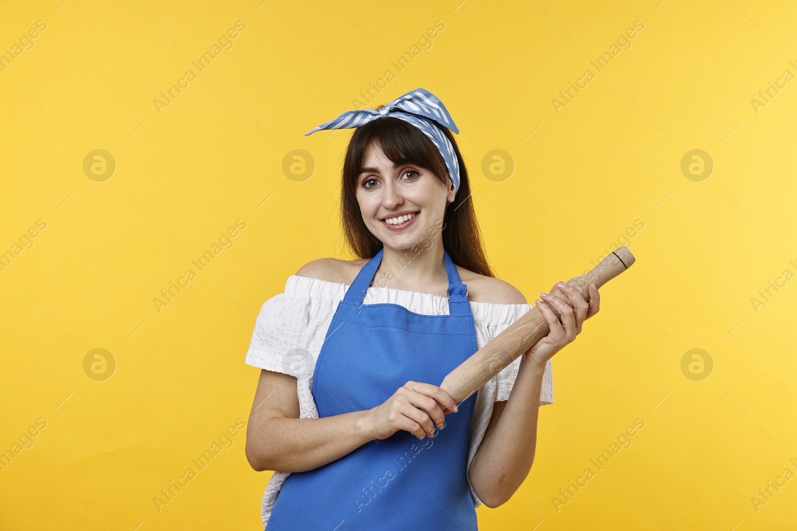 Photo of Happy woman with rolling pin on yellow background