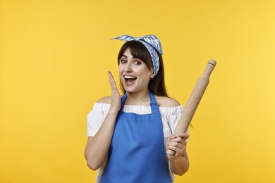 Photo of Excited woman with rolling pin on yellow background