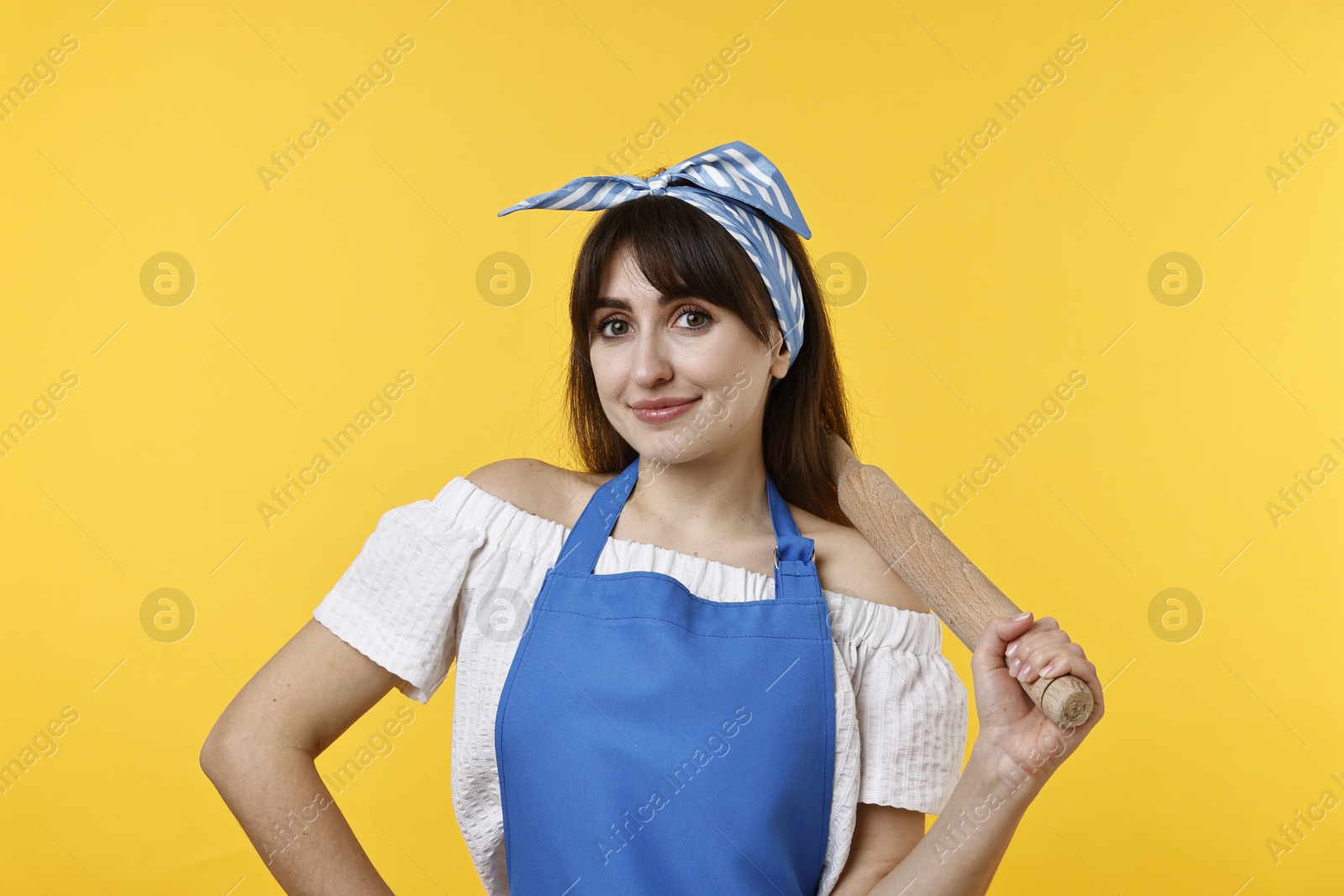 Photo of Happy woman with rolling pin on yellow background