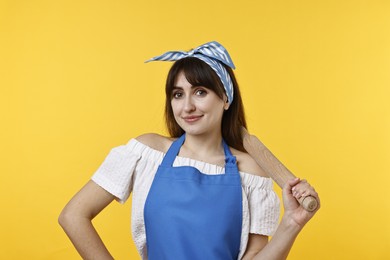 Photo of Happy woman with rolling pin on yellow background