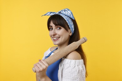 Photo of Happy woman with rolling pin on yellow background