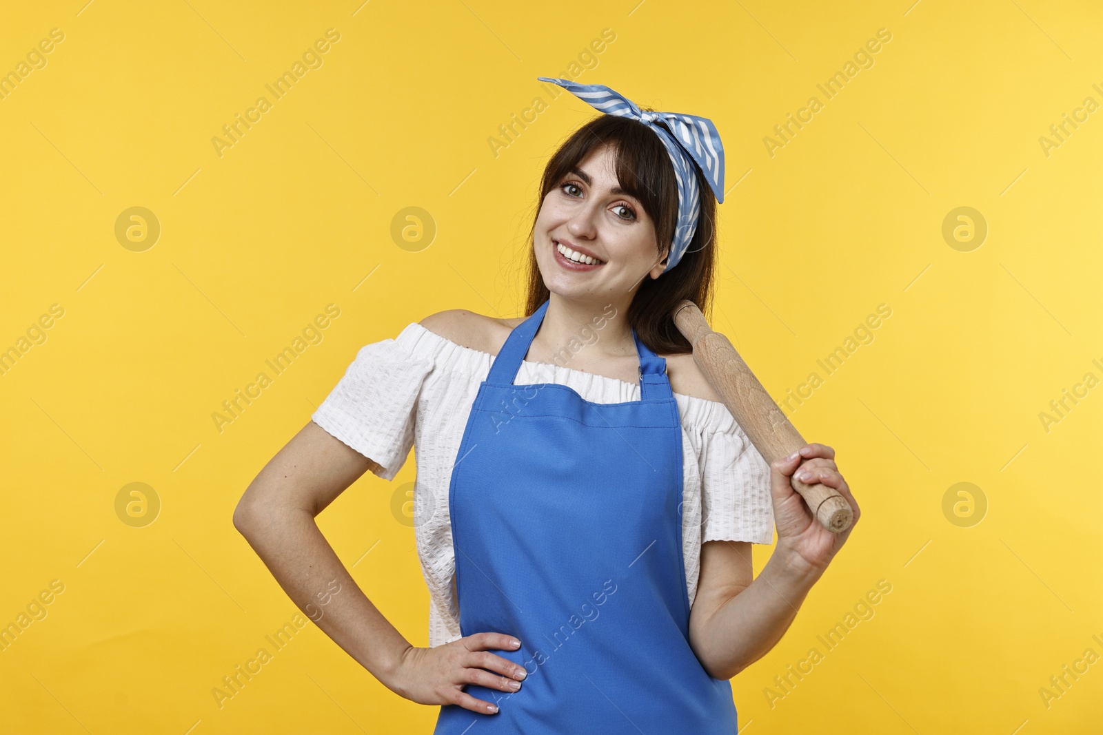 Photo of Happy woman with rolling pin on yellow background