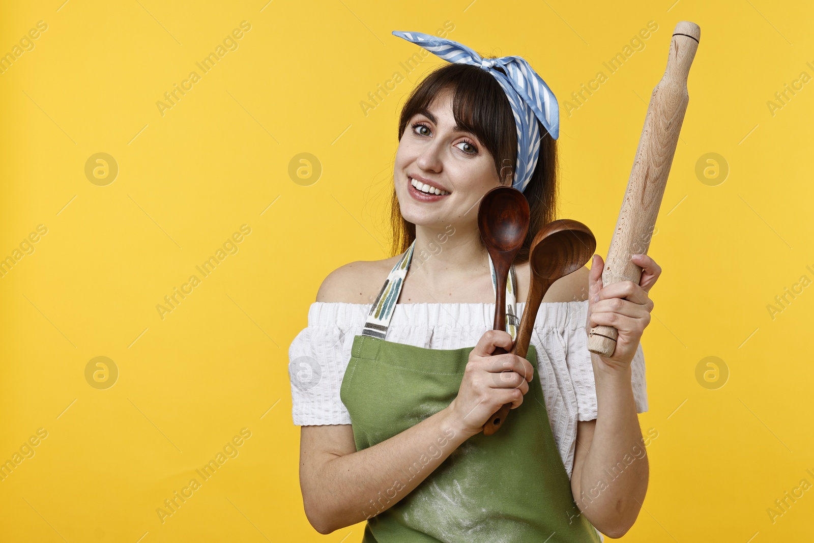 Photo of Happy woman with kitchen utensils on yellow background. Space for text