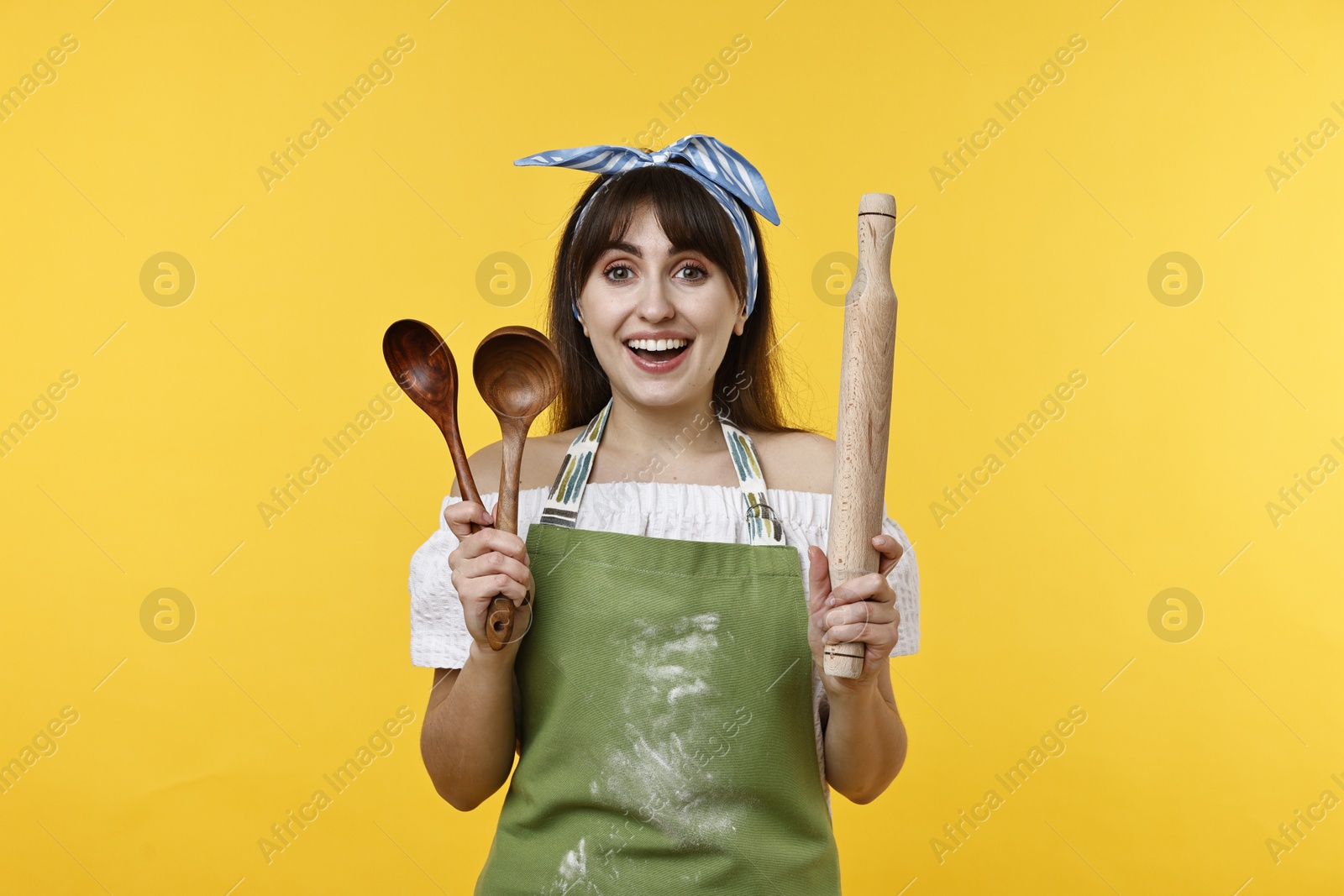 Photo of Happy woman with kitchen utensils on yellow background