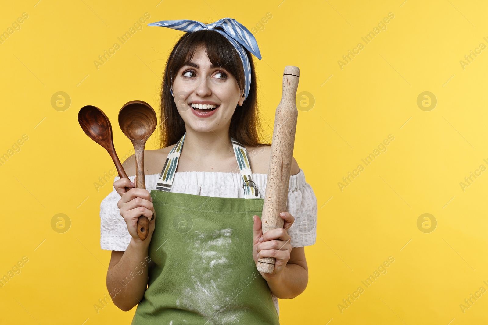 Photo of Happy woman with kitchen utensils on yellow background