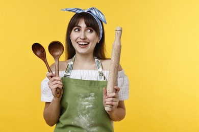 Photo of Happy woman with kitchen utensils on yellow background