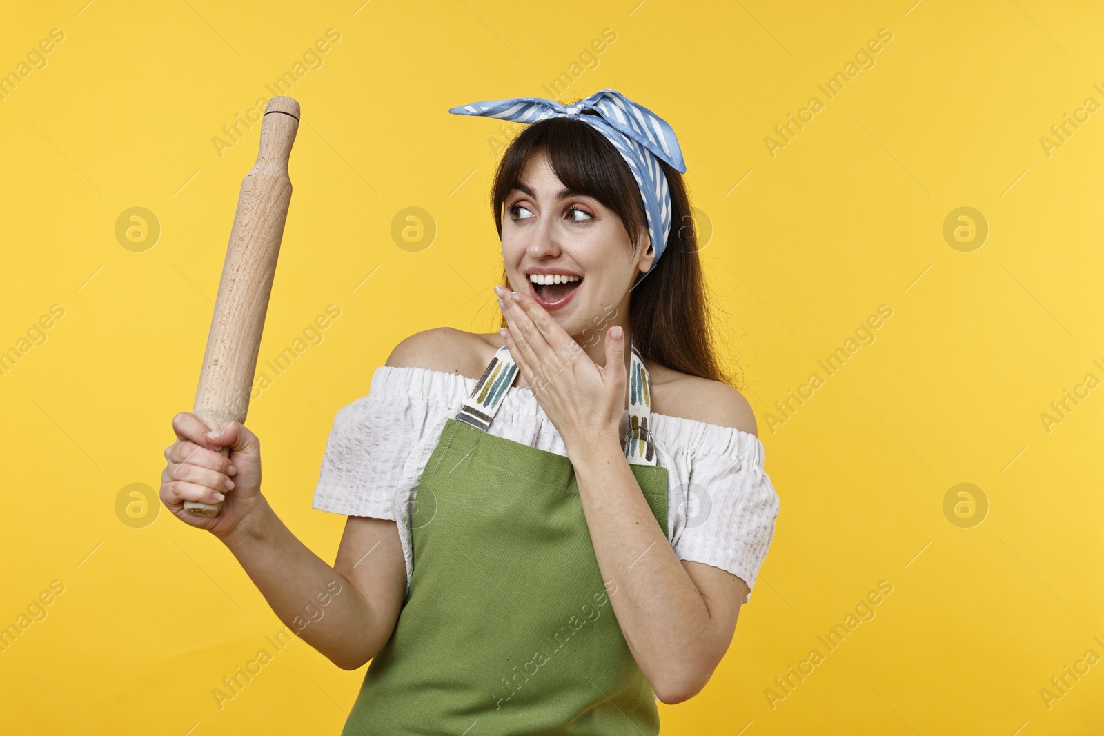 Photo of Excited woman with rolling pin on yellow background