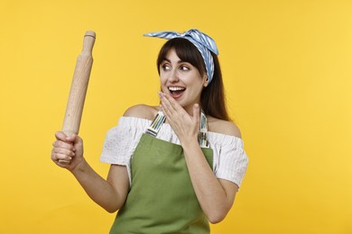 Photo of Excited woman with rolling pin on yellow background