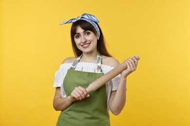 Photo of Happy woman with rolling pin on yellow background