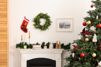 Photo of Decorated Christmas tree and fireplace in room. Festive interior design