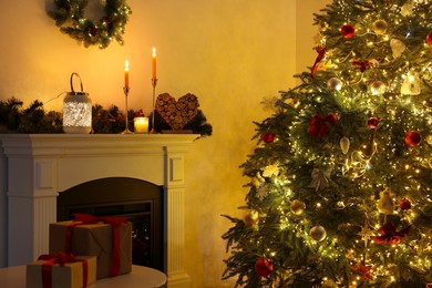 Decorated Christmas tree near fireplace in room. Festive interior design