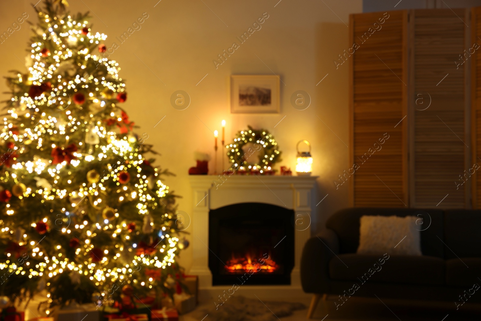 Photo of Blurred view of decorated Christmas tree near fireplace in room. Festive interior design