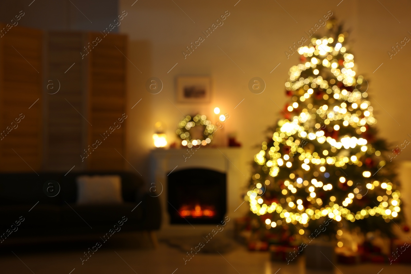 Photo of Blurred view of decorated Christmas tree near fireplace in room. Festive interior design