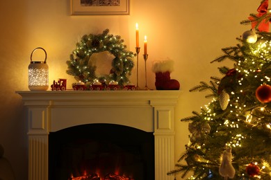 Photo of Decorated Christmas tree near fireplace in room, closeup. Festive interior design