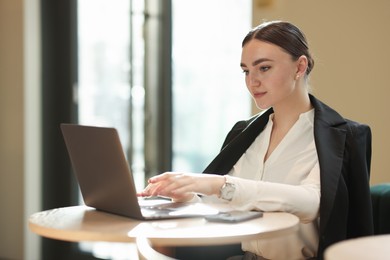 Photo of Woman in stylish formal suit working on laptop at table indoors