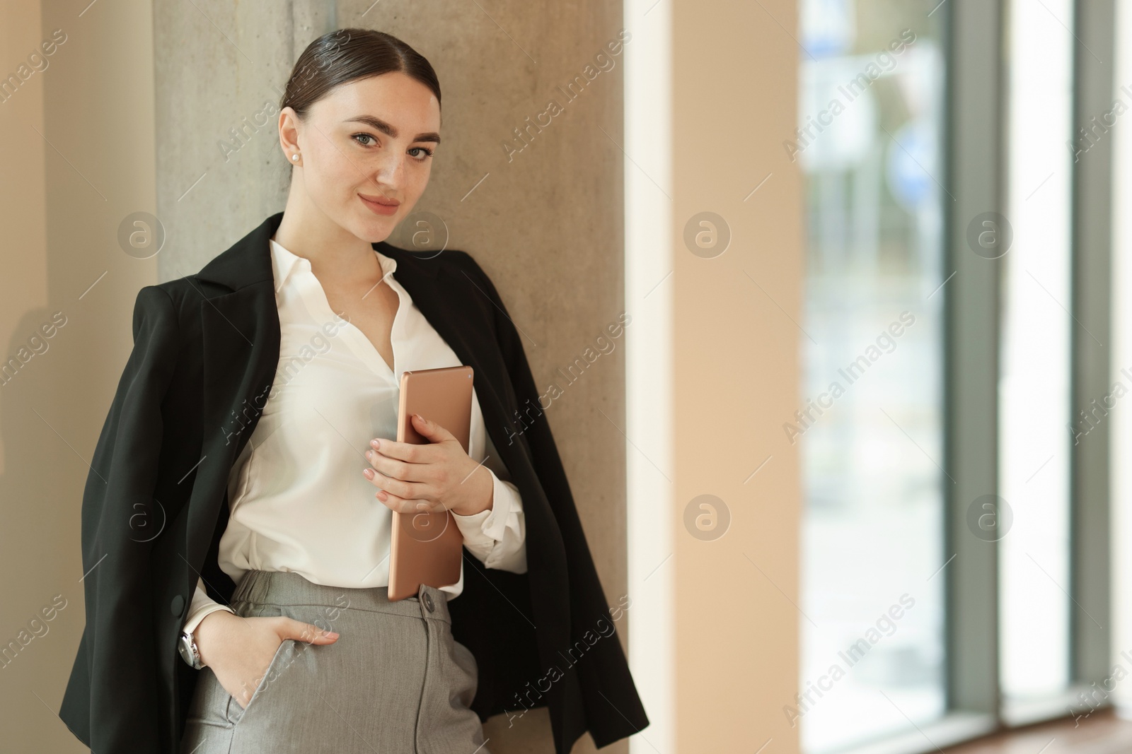 Photo of Woman in stylish formal suit with tablet indoors. Space for text