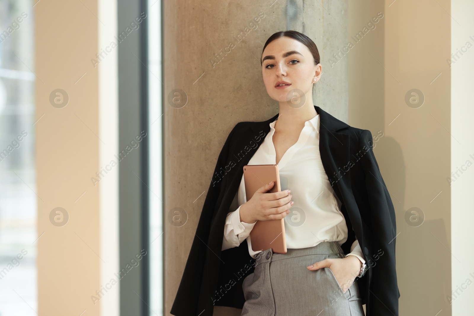 Photo of Woman in stylish formal suit with tablet indoors. Space for text