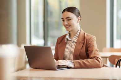 Photo of Woman in stylish formal suit with laptop at table indoors