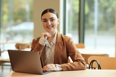 Photo of Woman in stylish formal suit with laptop at table indoors