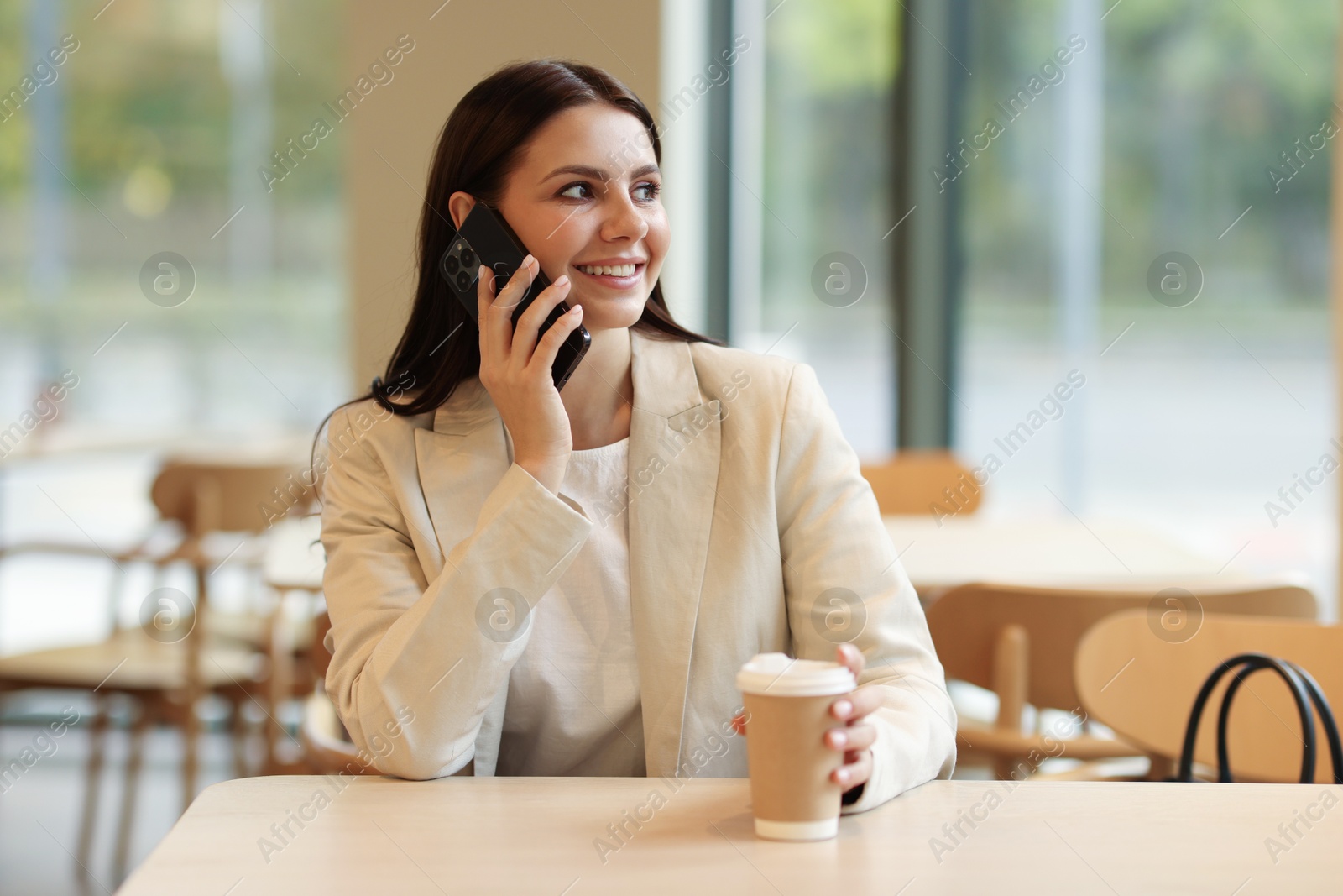 Photo of Woman in stylish formal suit talking on phone indoors