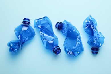 Photo of Crumpled plastic bottles on light blue background, flat lay