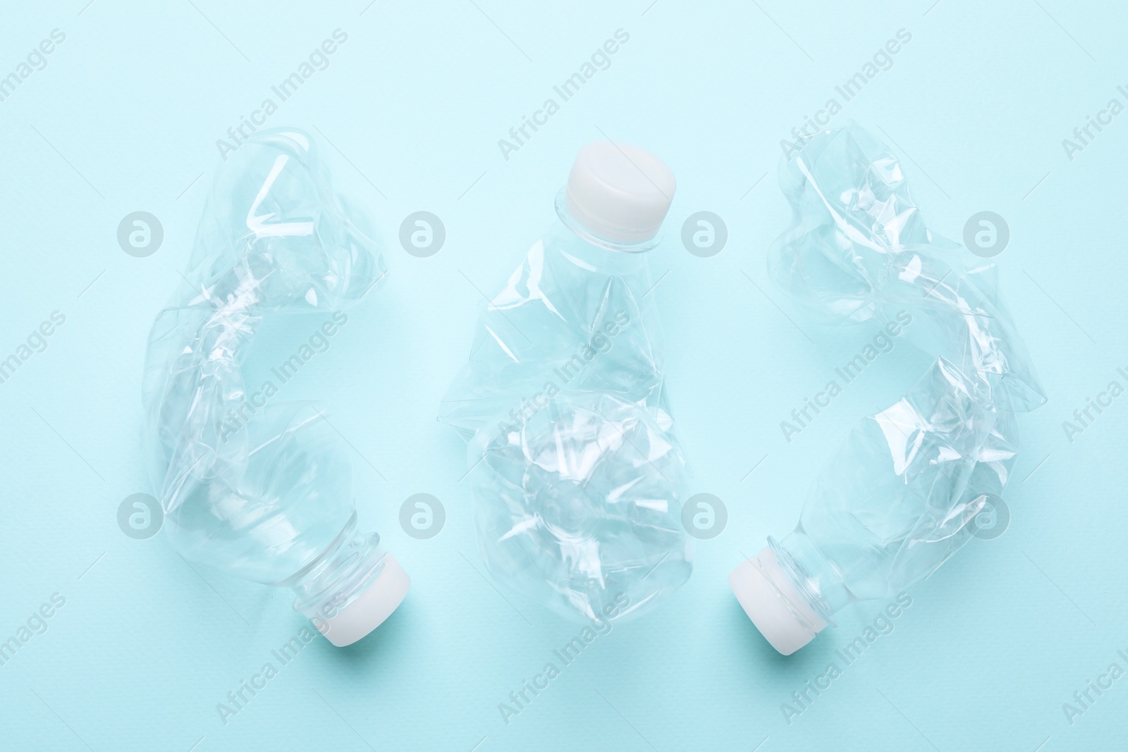 Photo of Crumpled plastic bottles on light blue background, flat lay