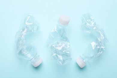 Photo of Crumpled plastic bottles on light blue background, flat lay