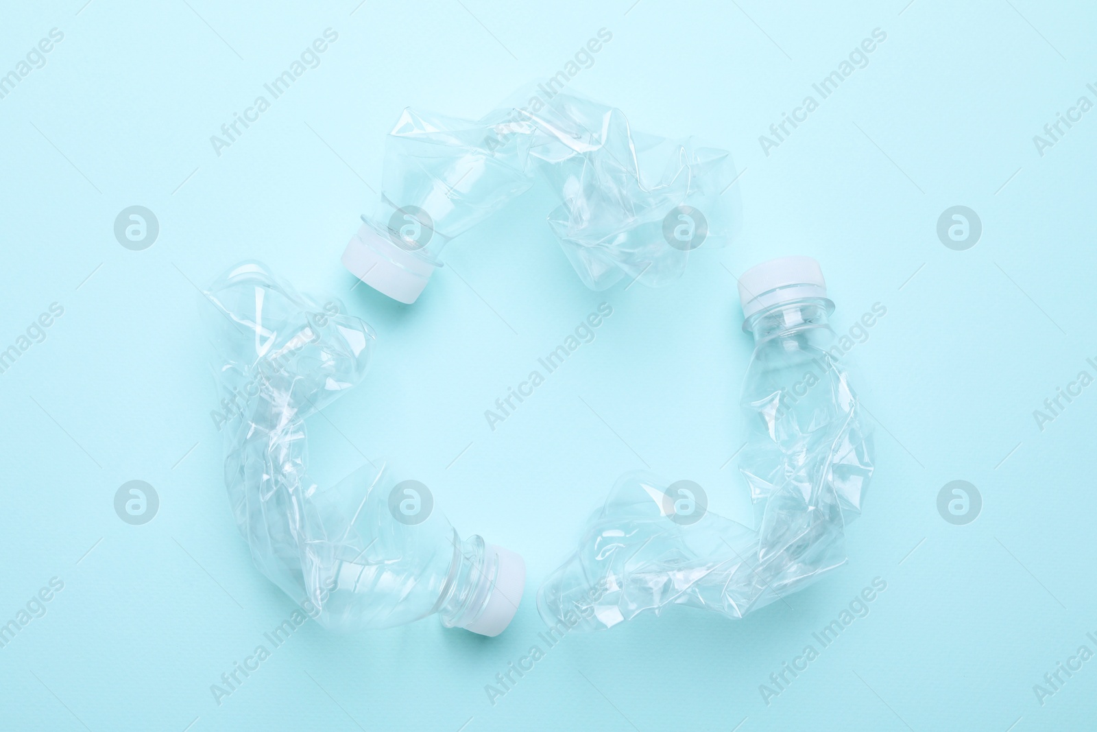 Photo of Crumpled plastic bottles on light blue background, flat lay