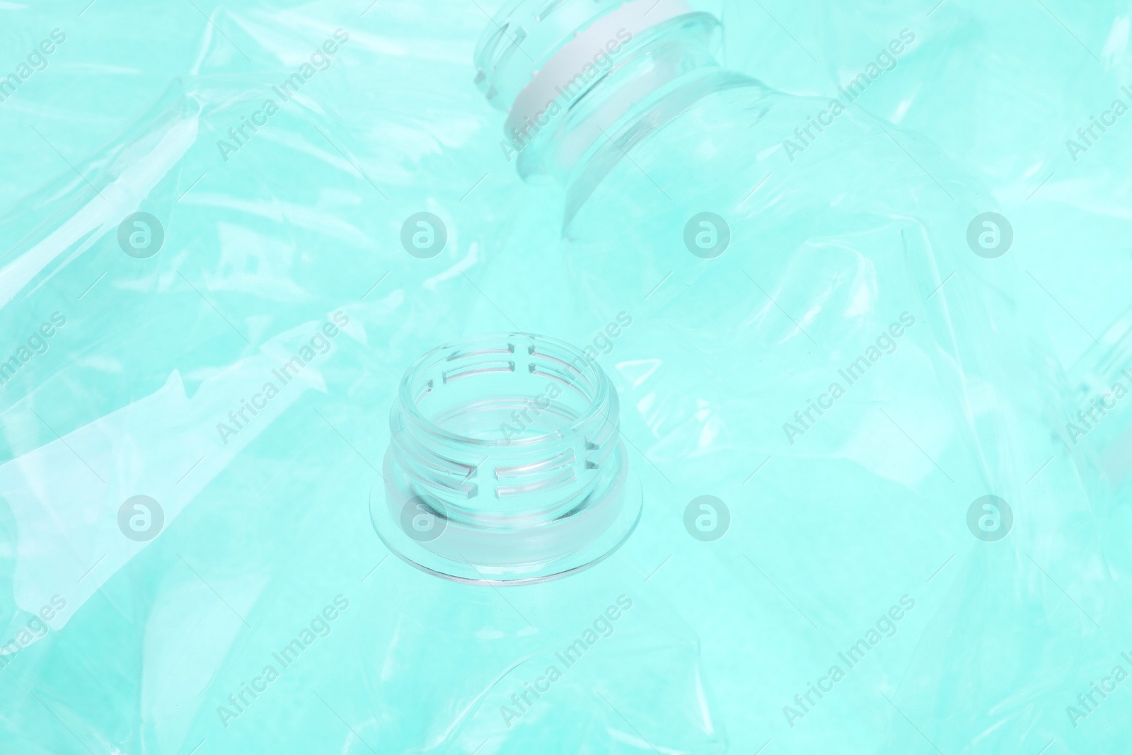 Photo of Crumpled plastic bottles on turquoise background, closeup