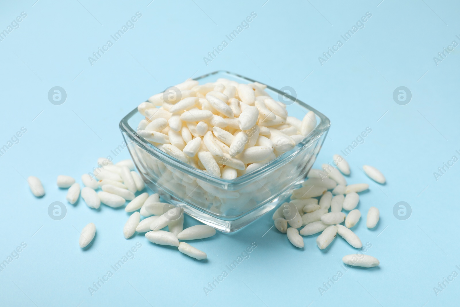 Photo of Puffed rice in bowl on light blue background, closeup