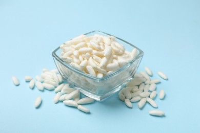 Photo of Puffed rice in bowl on light blue background, closeup