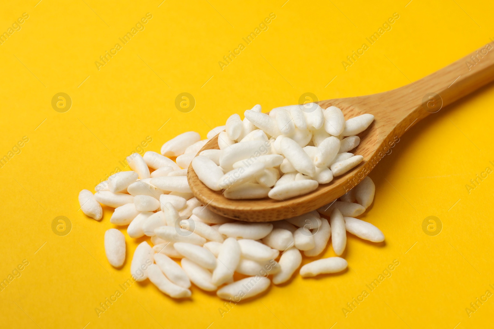 Photo of Spoon with puffed rice on yellow background, closeup