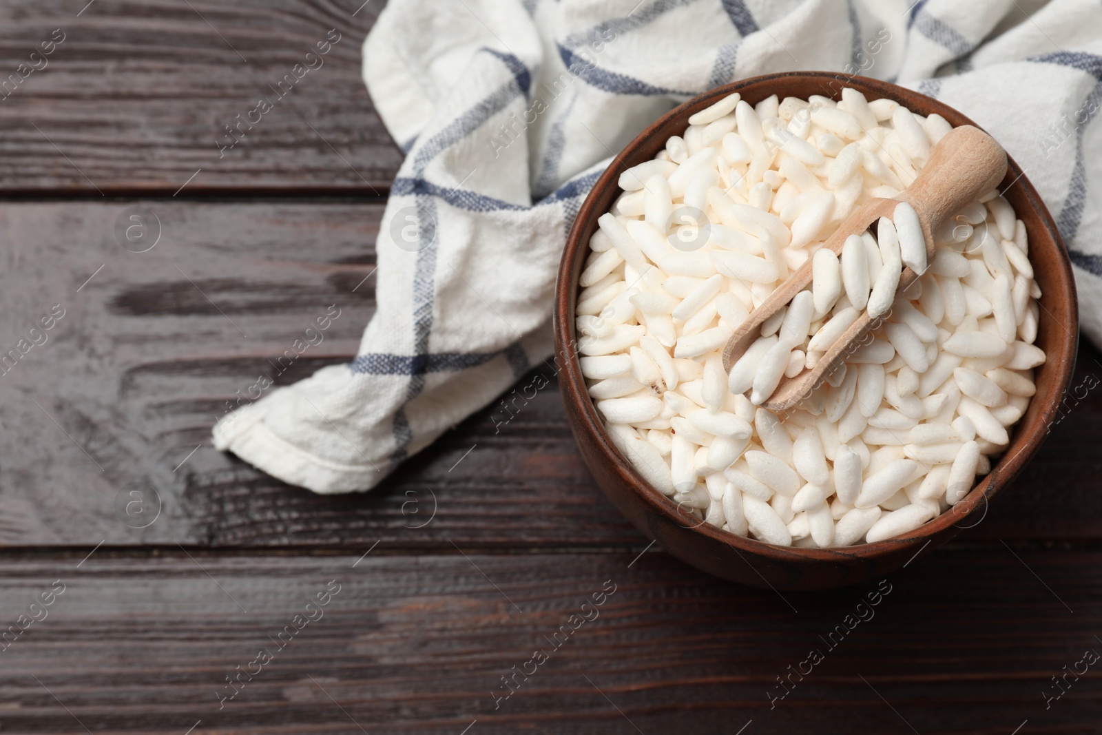 Photo of Puffed rice in bowl and scoop on wooden table, top view