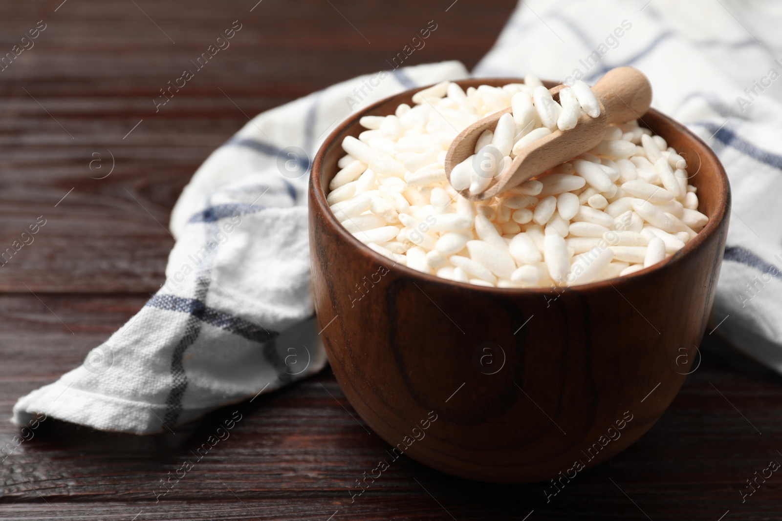 Photo of Puffed rice in bowl and scoop on wooden table, closeup