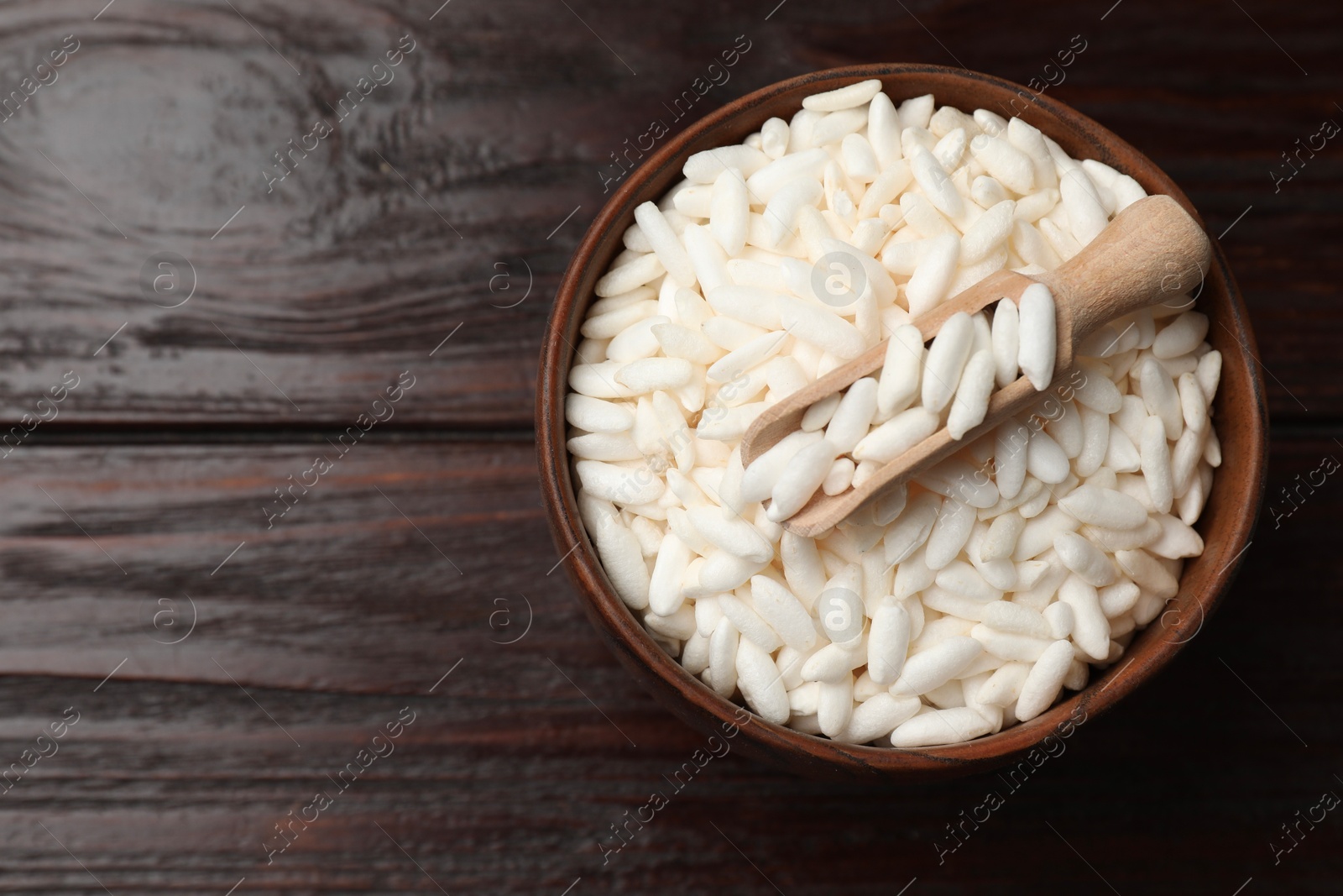 Photo of Puffed rice in bowl and scoop on wooden table, top view. Space for text