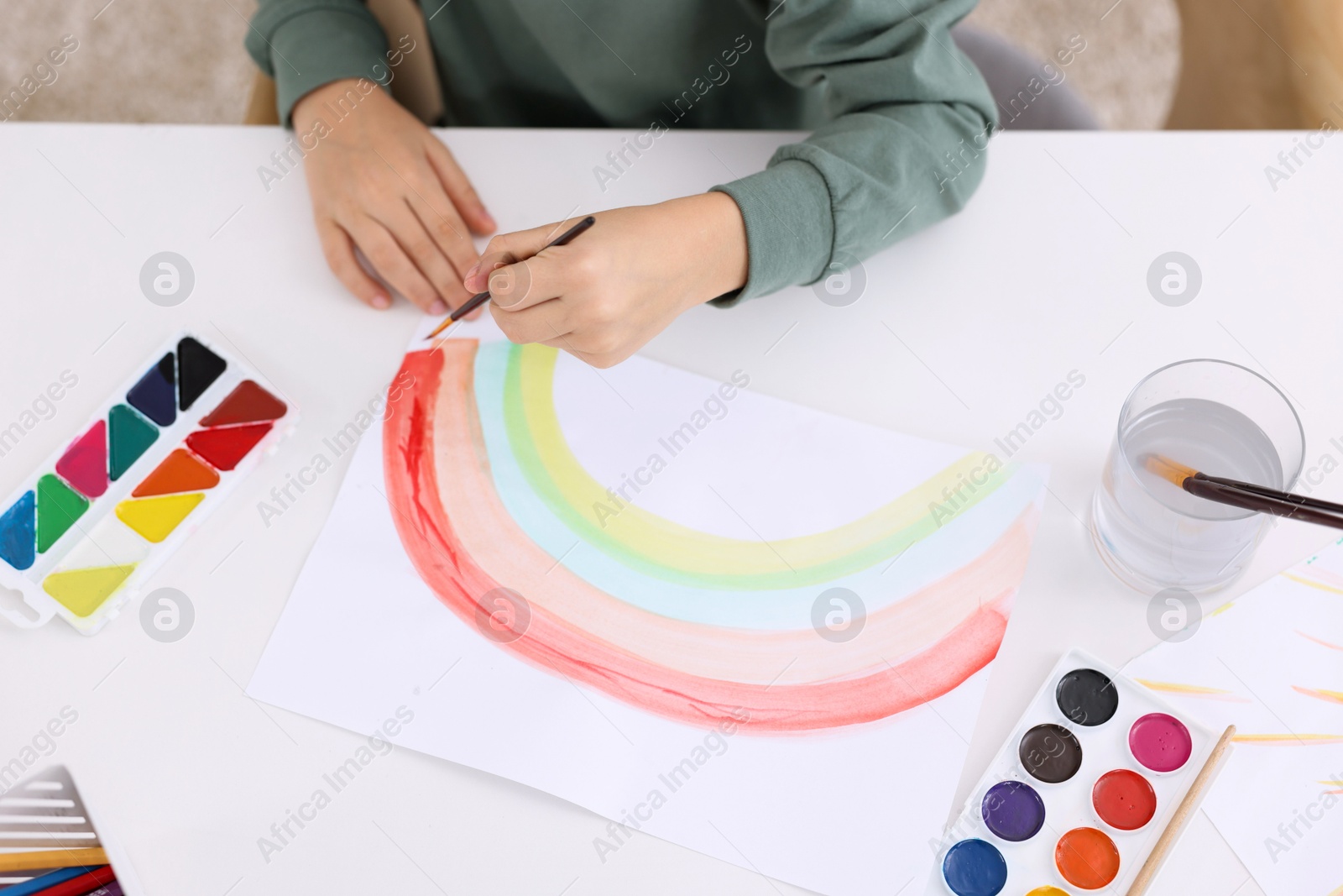 Photo of Little boy drawing at white table indoors, closeup