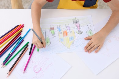 Photo of Boy drawing his family at white table indoors, above view