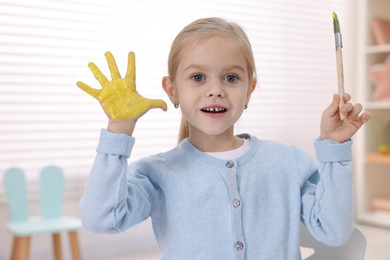 Photo of Cute girl drawing with palm in kindergarten