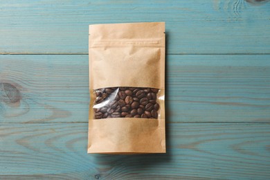 Photo of Paper pouch bag with coffee beans on light blue wooden table, top view