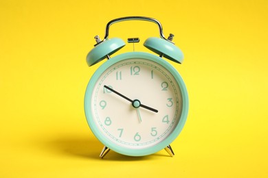 Photo of One turquoise alarm clock on yellow background