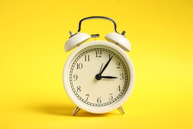 Photo of One white alarm clock on yellow background