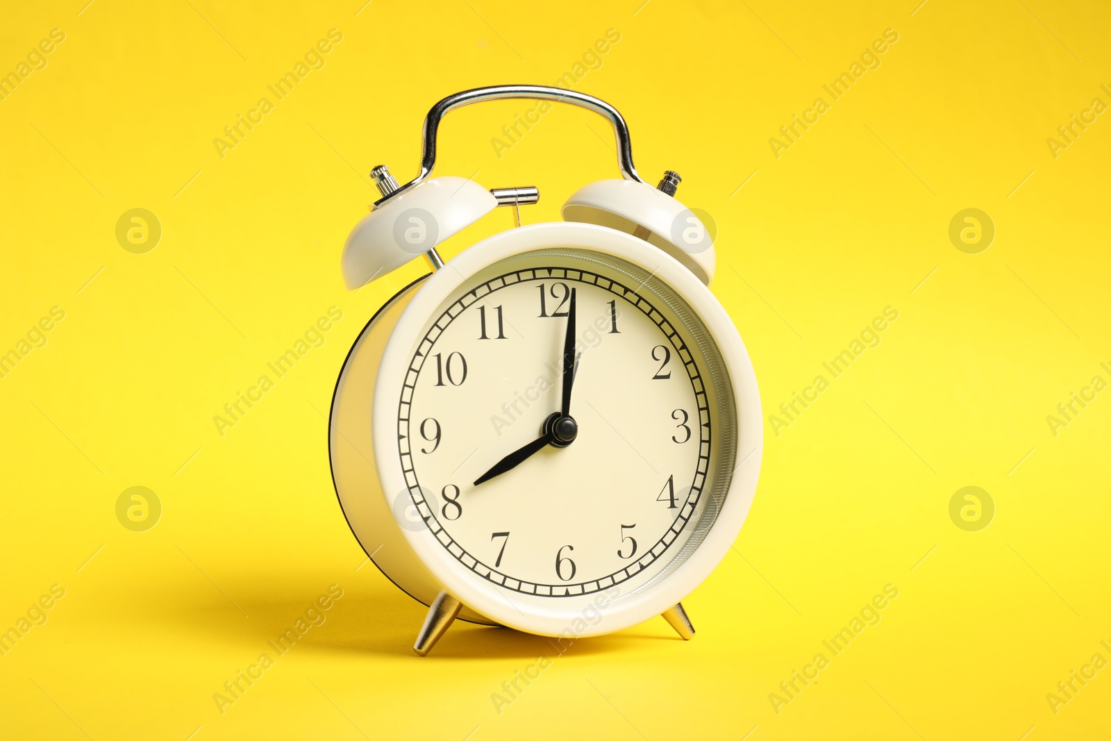 Photo of One white alarm clock on yellow background