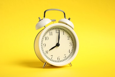 Photo of One white alarm clock on yellow background