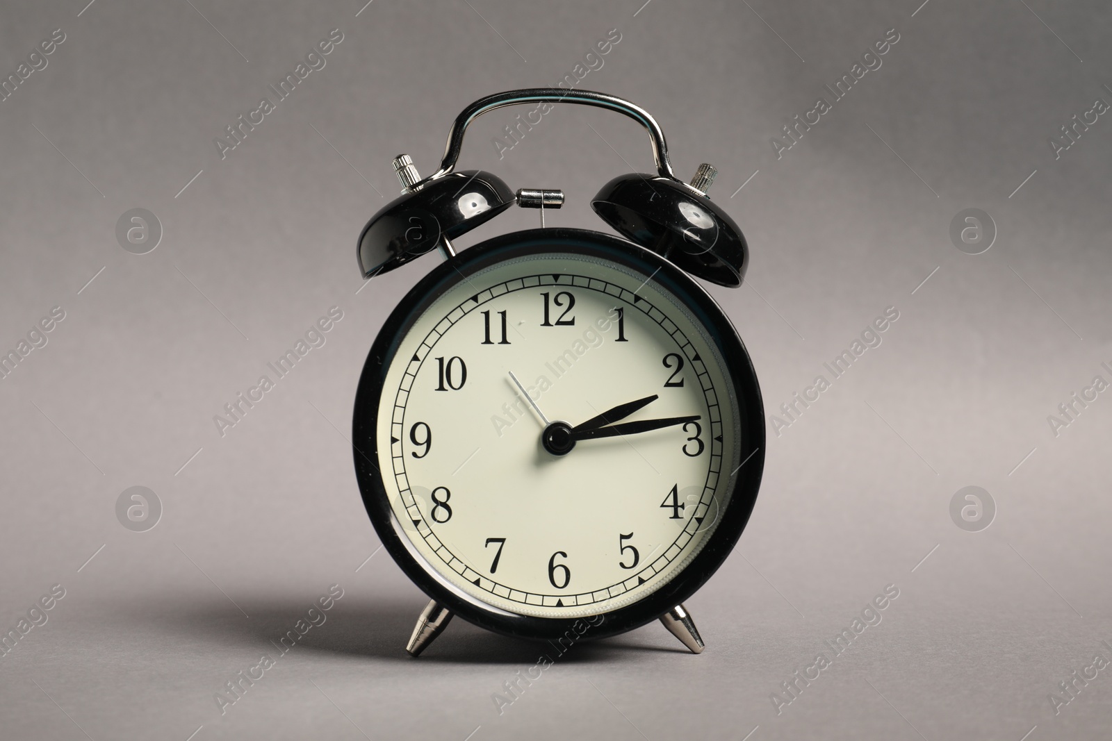 Photo of One black alarm clock on grey background