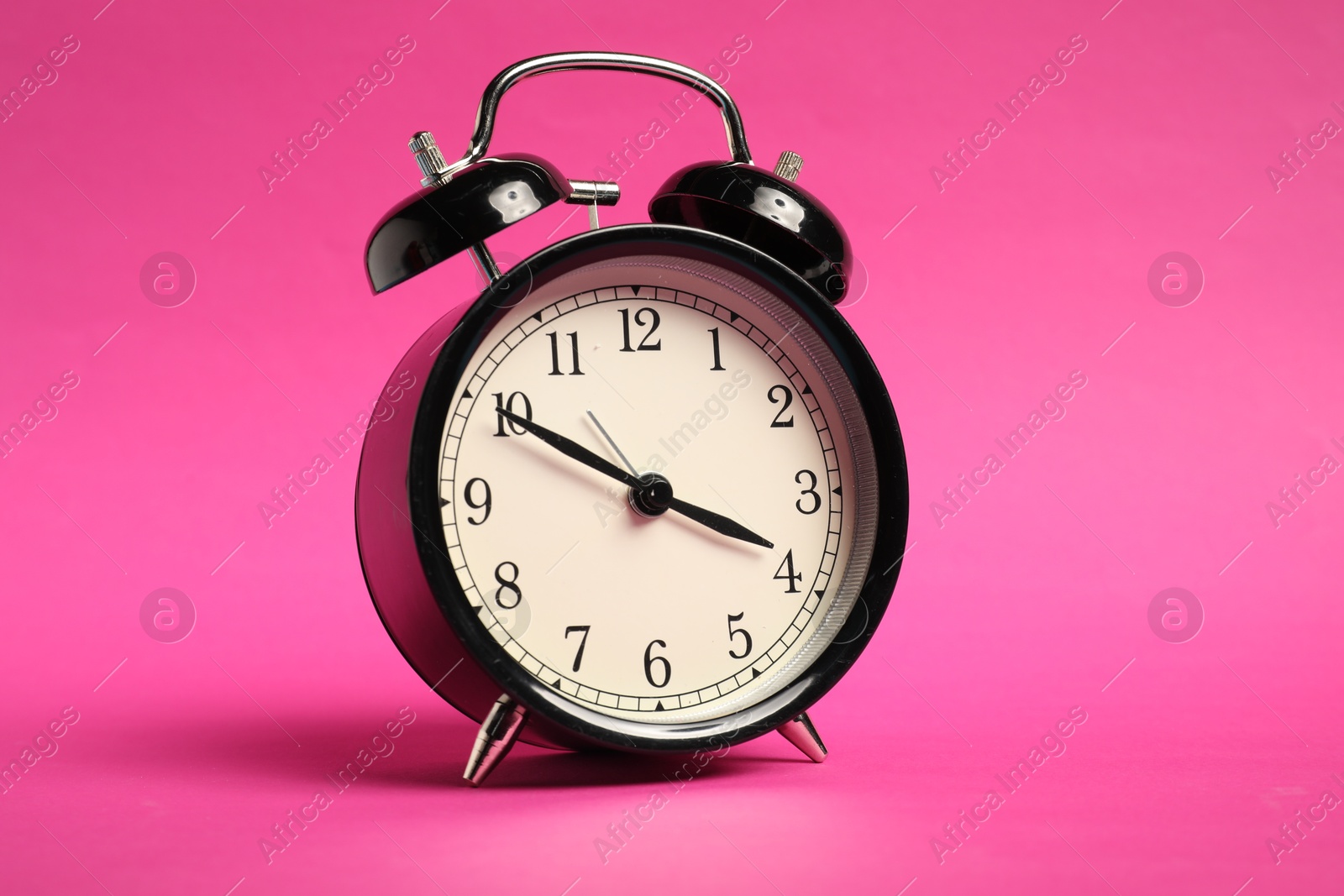 Photo of One black alarm clock on bright pink background