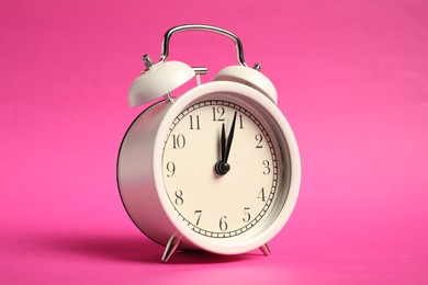 Photo of One white alarm clock on bright pink background